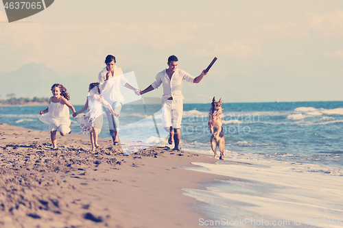 Image of happy family playing with dog on beach