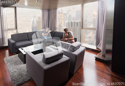 Image of two young men using a mobile phones  at home
