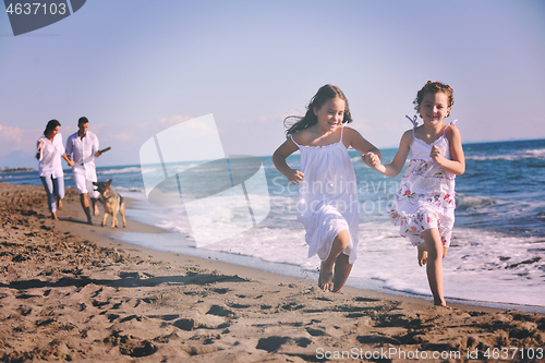 Image of happy family playing with dog on beach