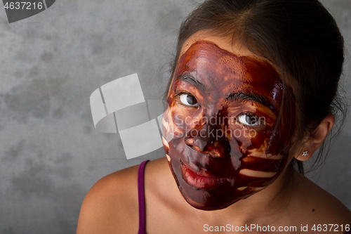 Image of young asian girl having fun with a chocolate mask