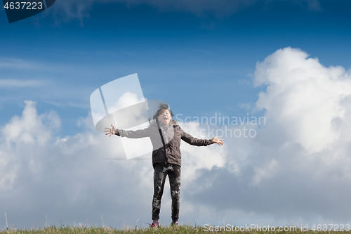 Image of Cute girl running jumping at the on a field in the summer