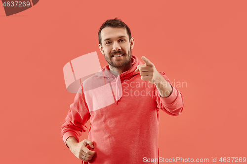 Image of The happy business man point you and want you, half length closeup portrait on coral background.