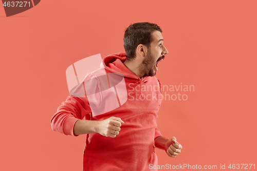 Image of The young emotional angry man screaming on coral studio background