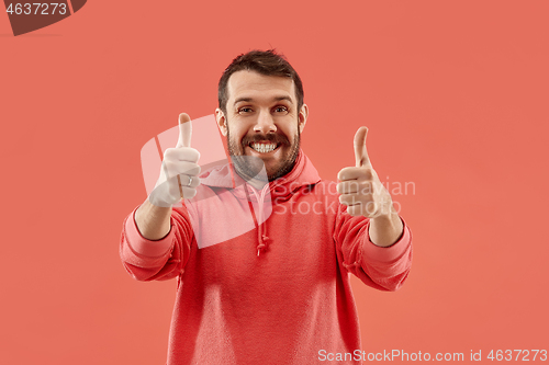 Image of The happy businessman standing and smiling against coral background.