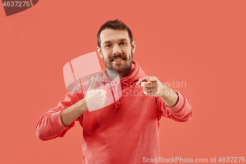 Image of The happy businessman standing and smiling against coral background.