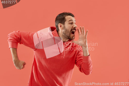 Image of Isolated on coral young casual man shouting at studio