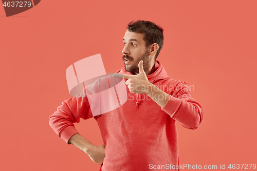 Image of The young attractive man looking suprised isolated on coral