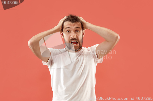 Image of The young attractive man looking suprised isolated on coral