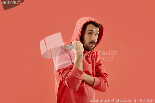 Image of The young man whispering a secret behind her hand over coral background