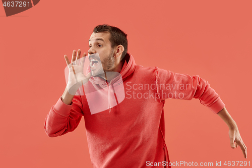 Image of Isolated on coral young casual man shouting at studio