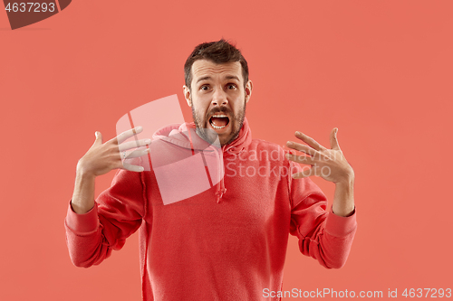 Image of The young attractive man looking suprised isolated on coral