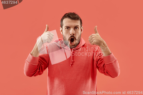 Image of The happy businessman standing and smiling against coral background.