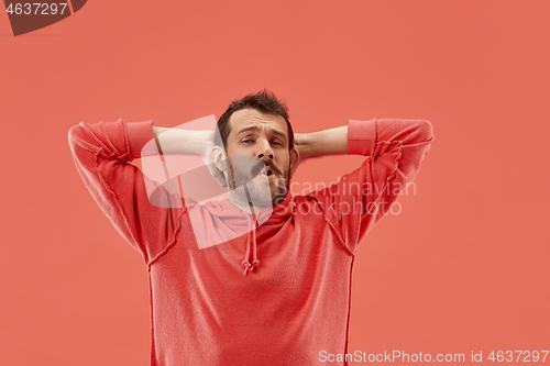 Image of Beautiful man looking suprised and bewildered isolated on coral