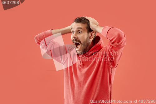 Image of The young emotional angry man screaming on coral studio background