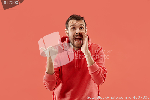 Image of The young attractive man looking suprised isolated on coral