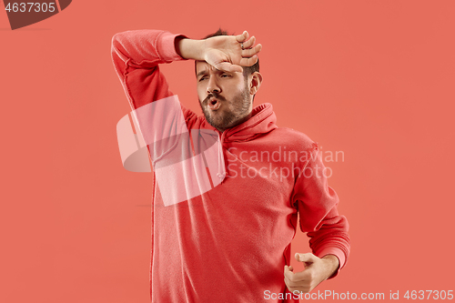 Image of Beautiful man looking suprised and bewildered isolated on coral