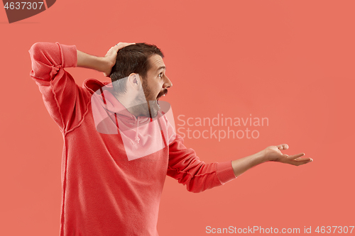 Image of The young attractive man looking suprised isolated on coral