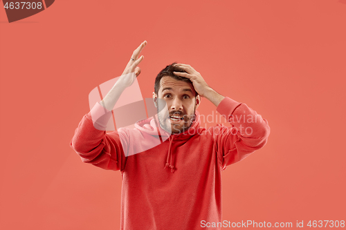 Image of Beautiful man looking suprised and bewildered isolated on coral