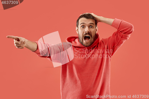 Image of The young emotional angry man screaming on coral studio background