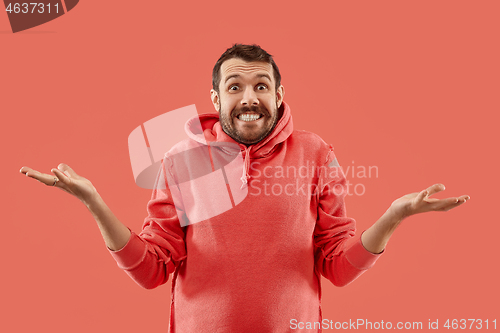 Image of The young attractive man looking suprised isolated on coral