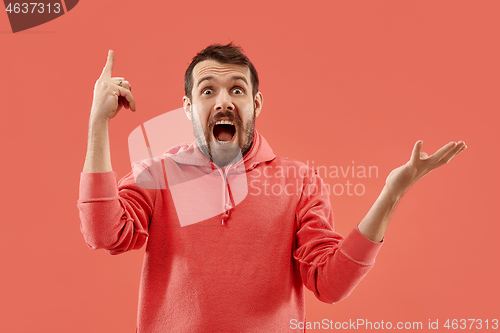 Image of The young attractive man looking suprised isolated on coral