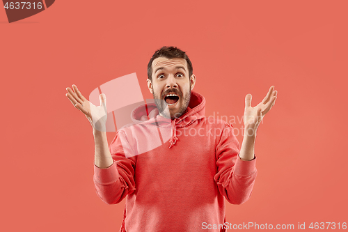 Image of The young attractive man looking suprised isolated on coral