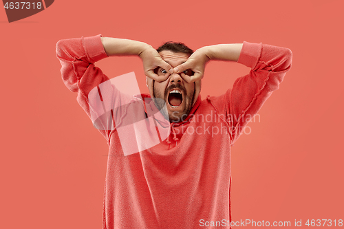 Image of The squint eyed man with weird expression isolated on coral