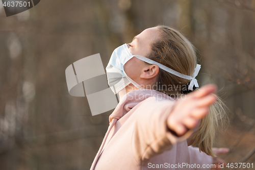 Image of Portrait of caucasian sporty woman wearing medical protection face mask while relaxing by taking a deep breath in forest. Corona virus, or Covid-19, is spreading all over the world