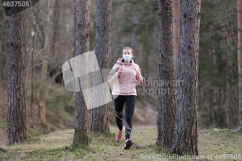 Image of Corona virus, or Covid-19, is spreading all over the world. Portrait of caucasian sporty woman wearing a medical protection face mask while running in nature.