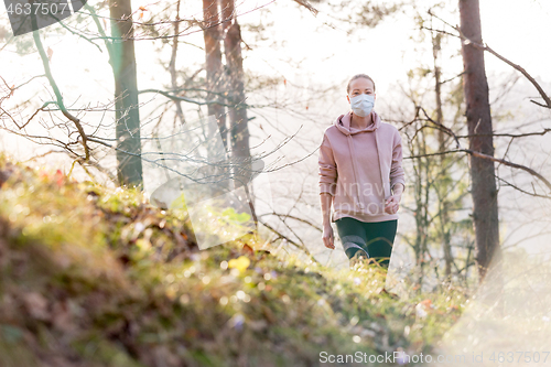 Image of Corona virus, or Covid-19, is spreading all over the world. Portrait of caucasian sporty woman wearing a medical protection face mask while walking in the forest. Corona virus.