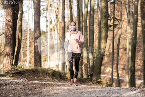 Image of Corona virus, or Covid-19, is spreading all over the world. Portrait of caucasian sporty woman wearing a medical protection face mask while running in nature.