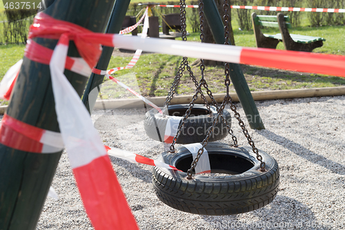 Image of Corona virus COVID-19 restriction. No people due to quarantine. Closed urban park. Empty park and playground. Stay at home compaign. Red warning tape on ramps and slides. Social distancing