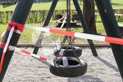 Image of Corona virus COVID-19 restriction. No people due to quarantine. Closed urban park. Empty park and playground. Stay at home compaign. Red warning tape on ramps and slides. Social distancing