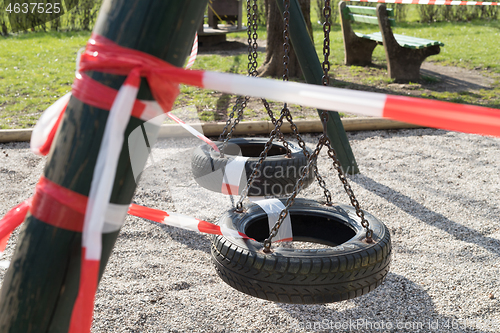 Image of Corona virus COVID-19 restriction. No people due to quarantine. Closed urban park. Empty park and playground. Stay at home compaign. Red warning tape on ramps and slides. Social distancing