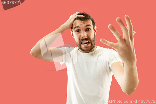 Image of Beautiful man looking suprised and bewildered isolated on coral