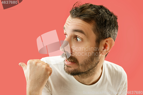 Image of The young man whispering a secret behind her hand over coral background