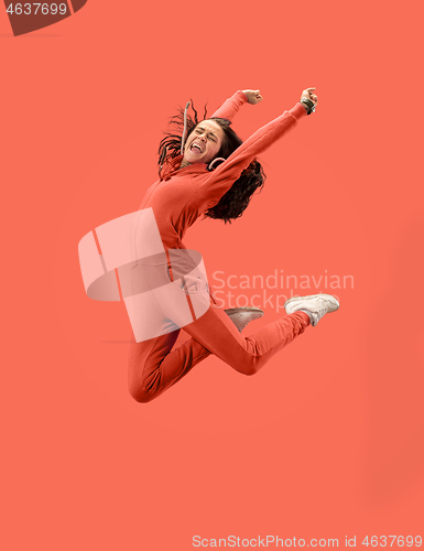 Image of Freedom in moving. Pretty young woman jumping against coral background