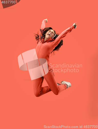 Image of Freedom in moving. Pretty young woman jumping against coral background