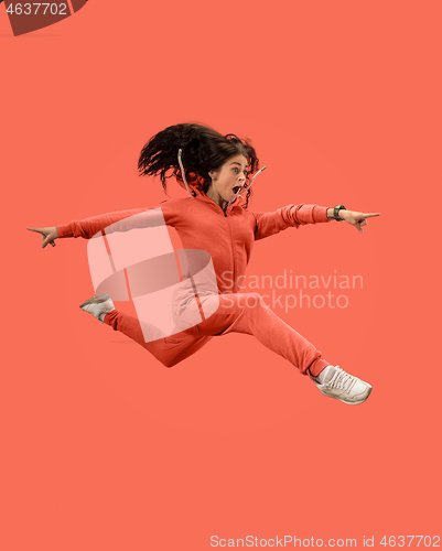 Image of Freedom in moving. Pretty young woman jumping against coral background