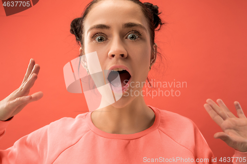 Image of Beautiful woman looking suprised isolated on coral