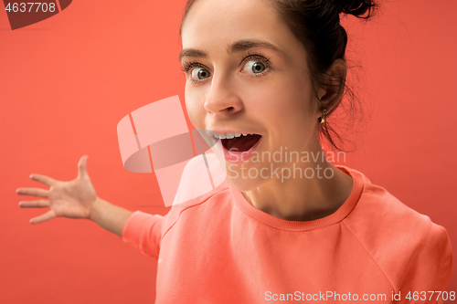 Image of Beautiful woman looking suprised isolated on coral