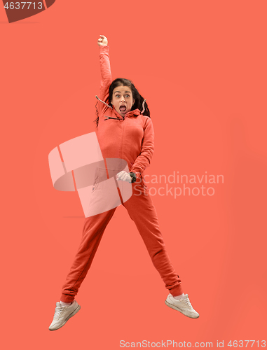 Image of Freedom in moving. Pretty young woman jumping against coral background