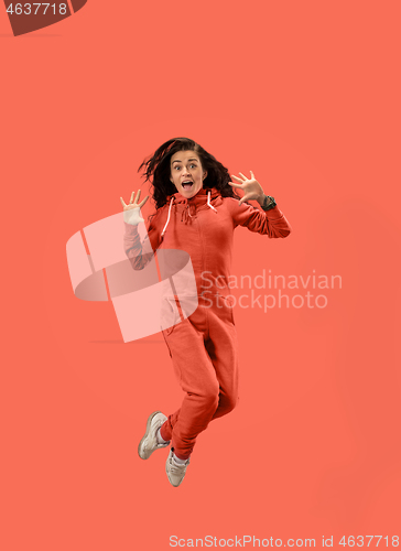 Image of Freedom in moving. Pretty young woman jumping against coral background