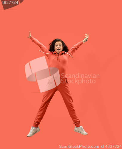 Image of Freedom in moving. Pretty young woman jumping against coral background