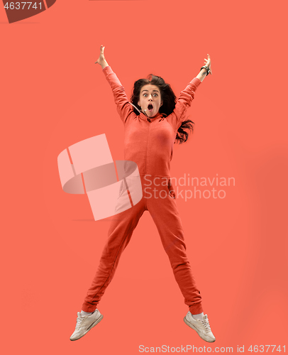 Image of Freedom in moving. Pretty young woman jumping against coral background