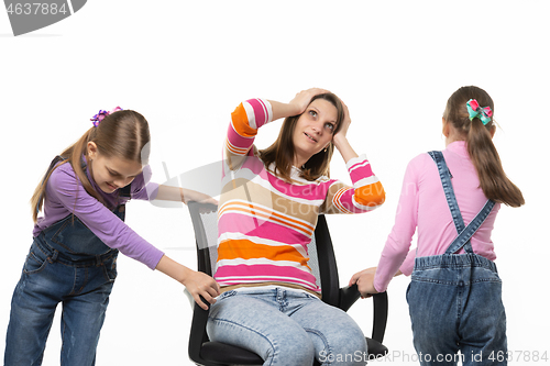 Image of Two daughters are spinning mom in an office chair, mom is spinning