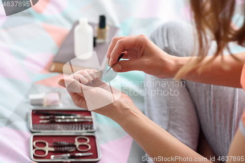 Image of A girl files nails with a nail file, cosmetics in the background