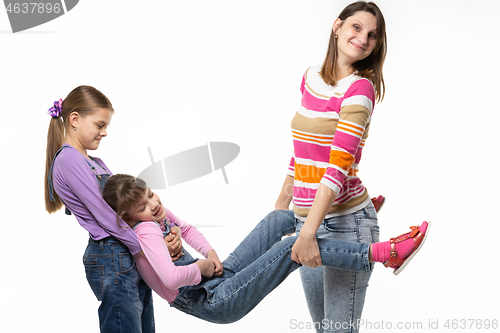 Image of Mom and the eldest daughter took the youngest daughter by the arms and legs
