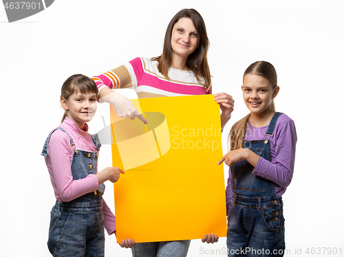 Image of Mom and two daughters hold an orange sign in their hands and point to it