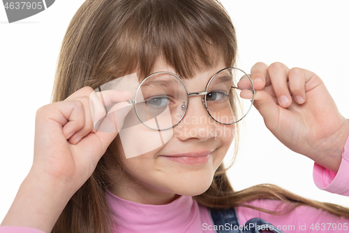 Image of Happy girl adjusts his glasses and looks into the frame, close-up